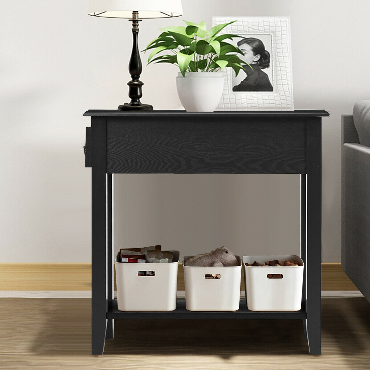 Black wooden nightstand with lamp, plant, framed photo, and three white storage baskets on shelf on Tampa Home & Garden Store
