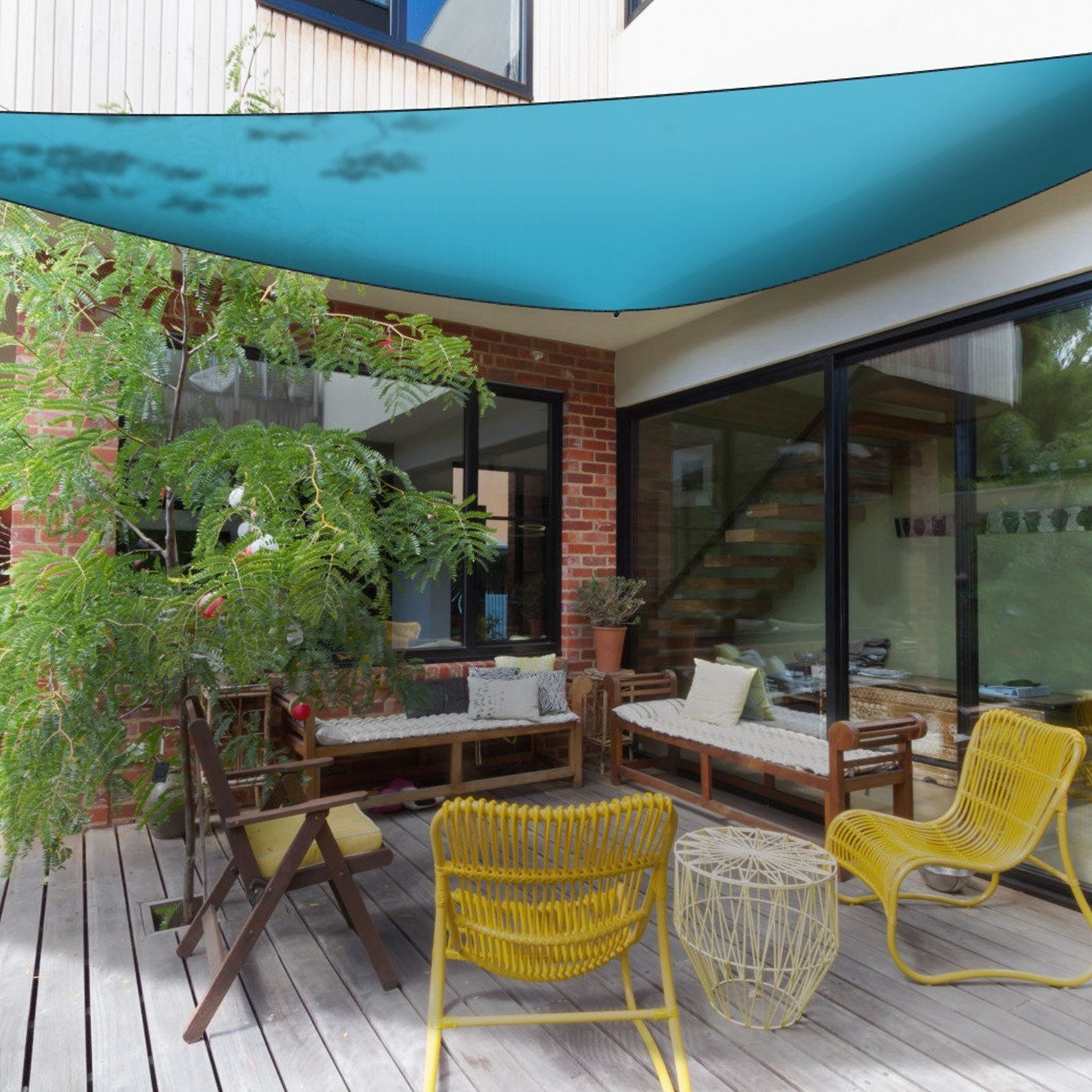 GemGear teal shade sail canopy over wooden deck with brick wall and yellow patio chairs on Tampa Home & Garden Store