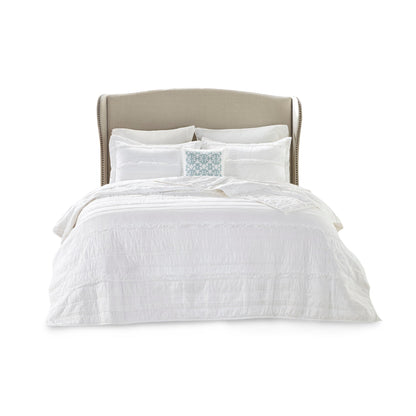 White reversible quilt set with embroidered blue throw pillow on beige upholstered bed on Tampa Home & Garden Store