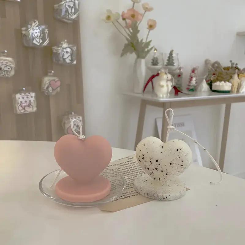 Two heart-shaped candle molds, pink silicone and white speckled epoxy, with wicks on Tampa Home & Garden Store