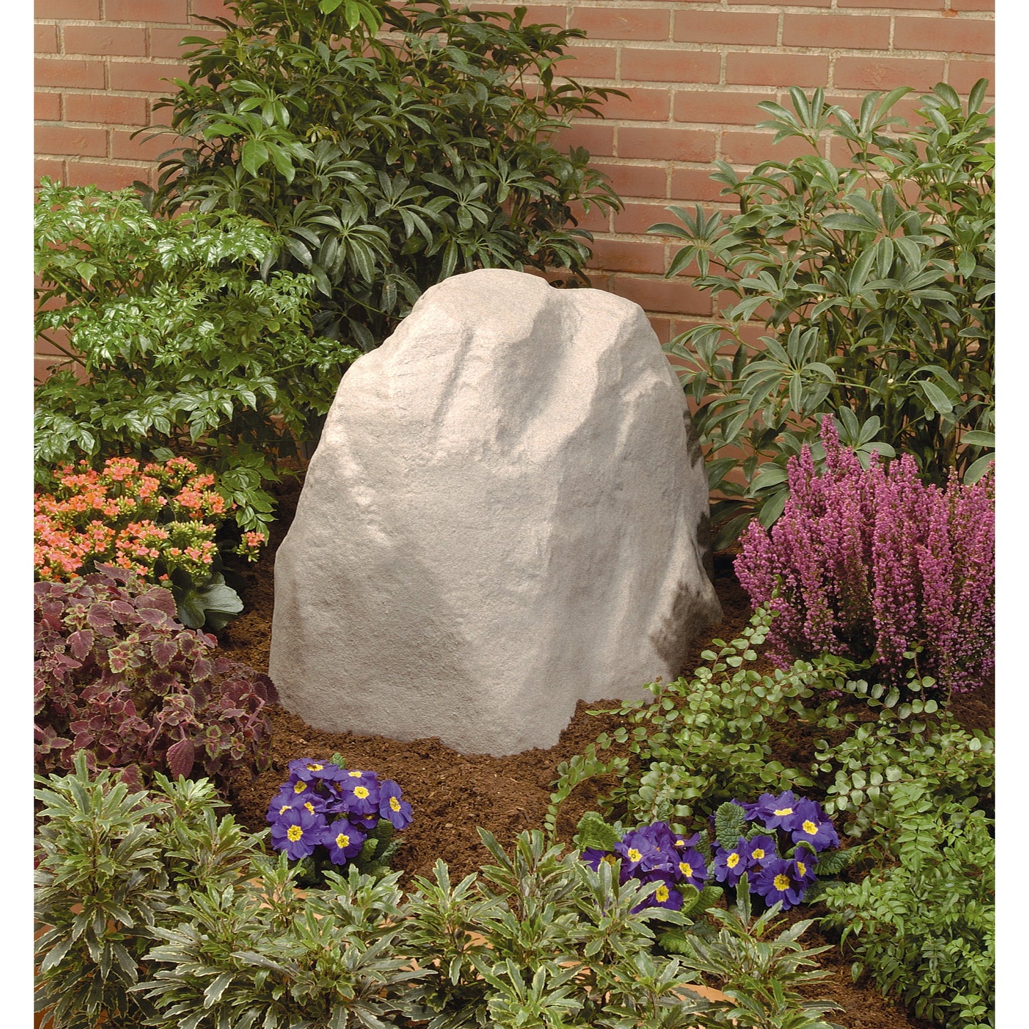 Sandstone Rock Valve Box Cover 53017 for underground irrigation amid shrubs and brick wall on Tampa Home & Garden Store