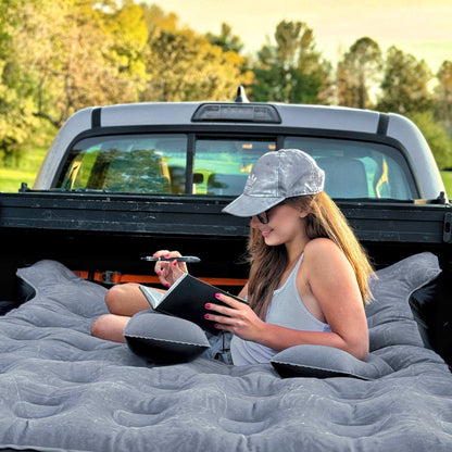 Dikasun 6-6.5 ft pickup bed air mattress, gray quilted in pickup with woman reading a notebook on Tampa Home & Garden Store