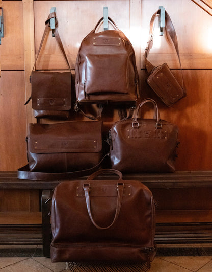 The Field Duffle by Will Leather Goods, brown leather duffle on display with leather bags on Tampa Home & Garden Store