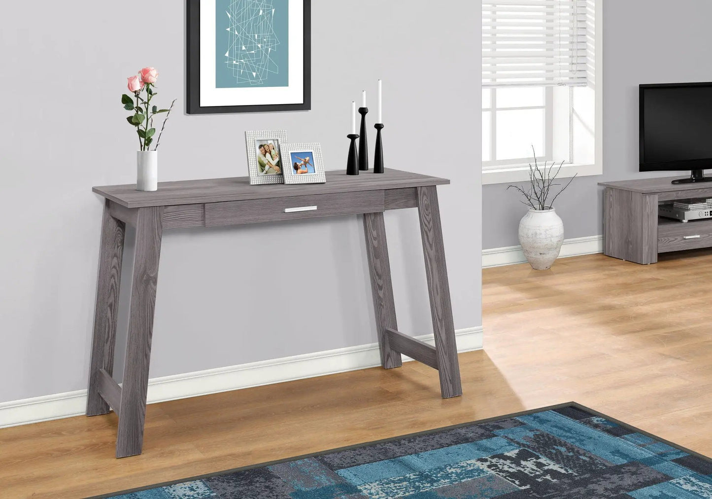 Writing desk in gray wood finish with a centered storage drawer and two photo frames on top on Tampa Home & Garden Store