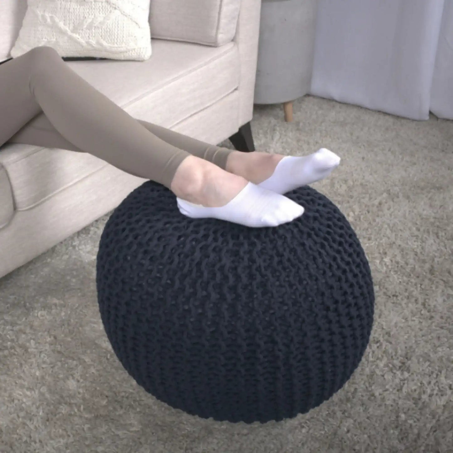 Bordeaux Knitted Cotton Round Pouf Ottoman Floor Cushion on beige carpet beside a sofa on Tampa Home & Garden Store