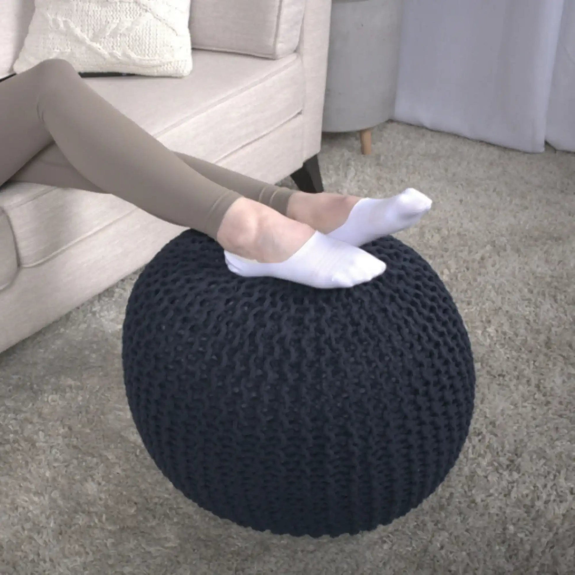 Bordeaux Knitted Cotton Round Pouf Ottoman Floor Cushion on beige carpet beside a sofa on Tampa Home & Garden Store