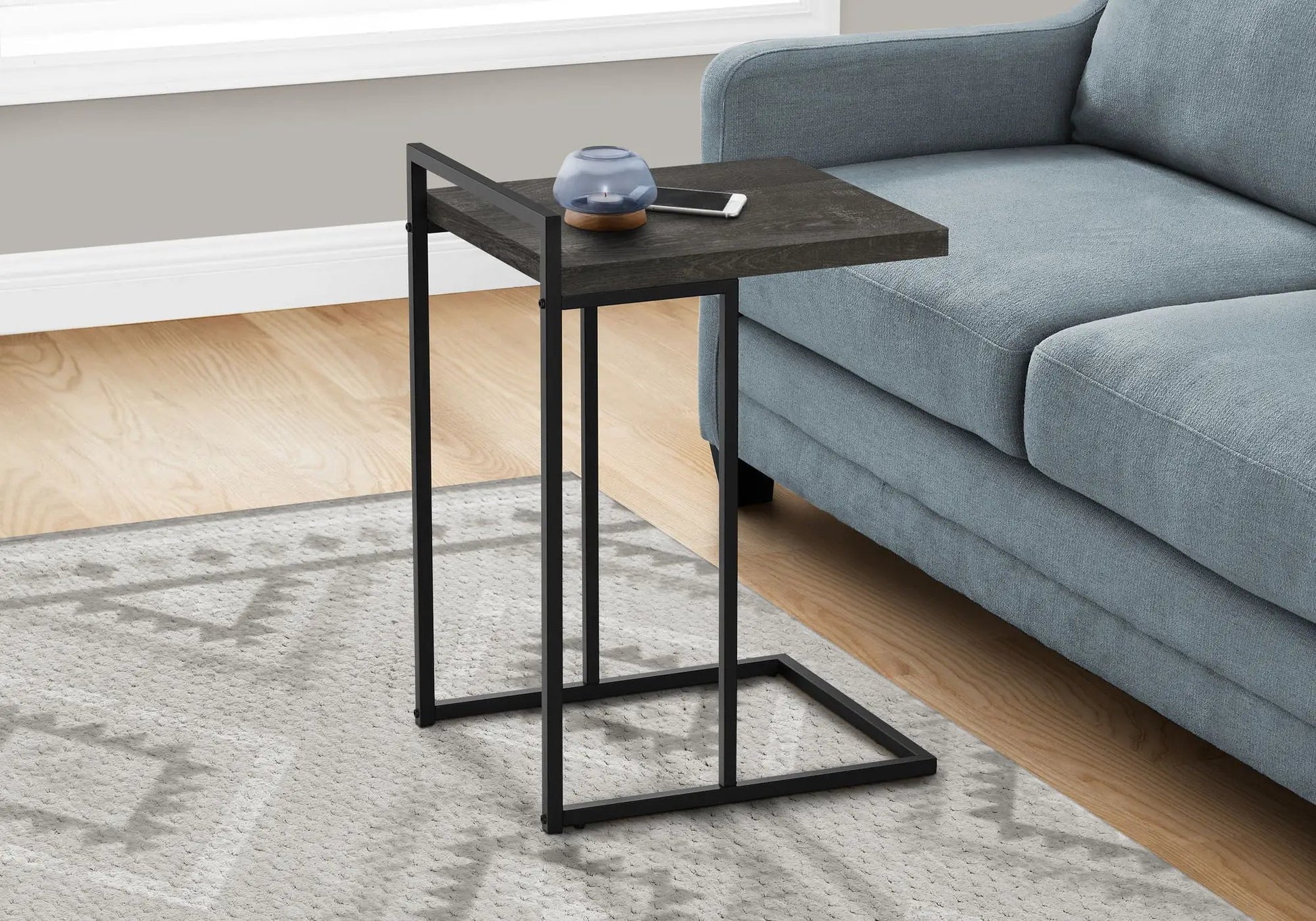 C-Shaped accent table with dark wood top and black metal frame beside blue sofa on Tampa Home & Garden Store