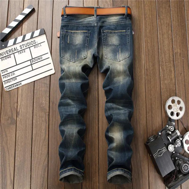 Men's blue distressed straight jeans with back-pocket wear and brown belt, laid on wooden floor on Tampa Home & Garden Store