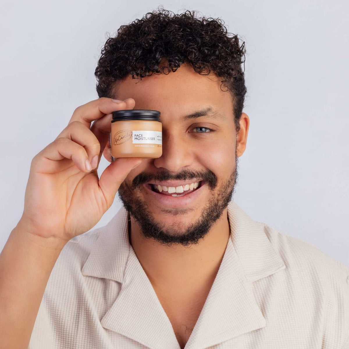 Face Moisturiser from UpCircle in tan jar with visible label, held by smiling man on Tampa Home & Garden Store