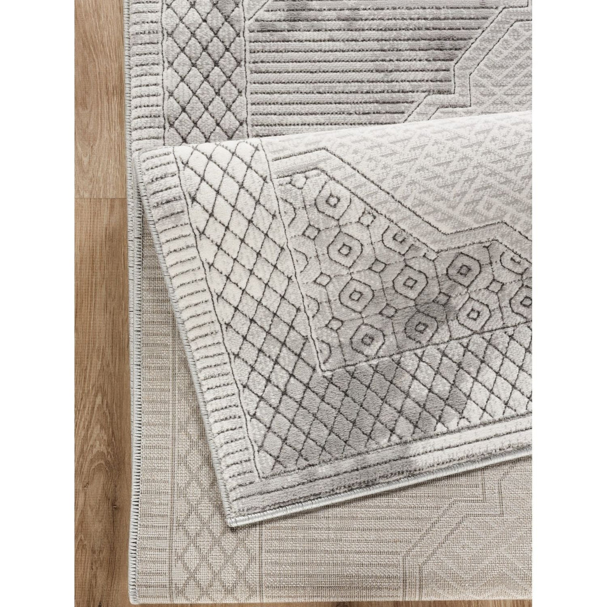 Area rug gray medallion with geometric 3D detail layered over a geometric rug on wood floor on Tampa Home & Garden Store