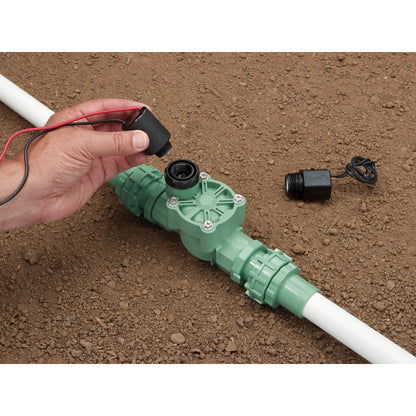 Battery-Powered Sprinkler Controller by Orbit Irrigation with red/black leads beside green irrigation valve on dirt on Tampa Home & Garden Store