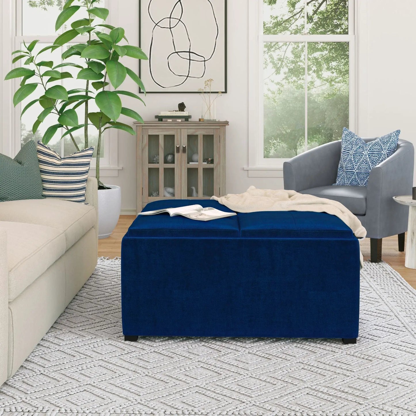 Avalon square storage ottoman in blue velvet placed in a bright living room with beige sofa on Tampa Home & Garden Store