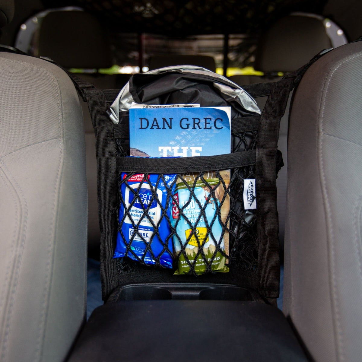 Flatirons Overland Universal Seat Divider Storage Net in black mesh with a book on Tampa Home & Garden Store