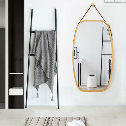 Oval wooden-framed wall mirror beside a black metal ladder towel rack with a gray knit throw on Tampa Home & Garden Store