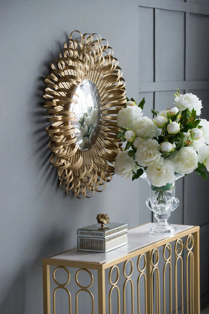 Sunburst gold wall mirror with woven metal loops and a central reflective disk on gray wall on Tampa Home & Garden Store