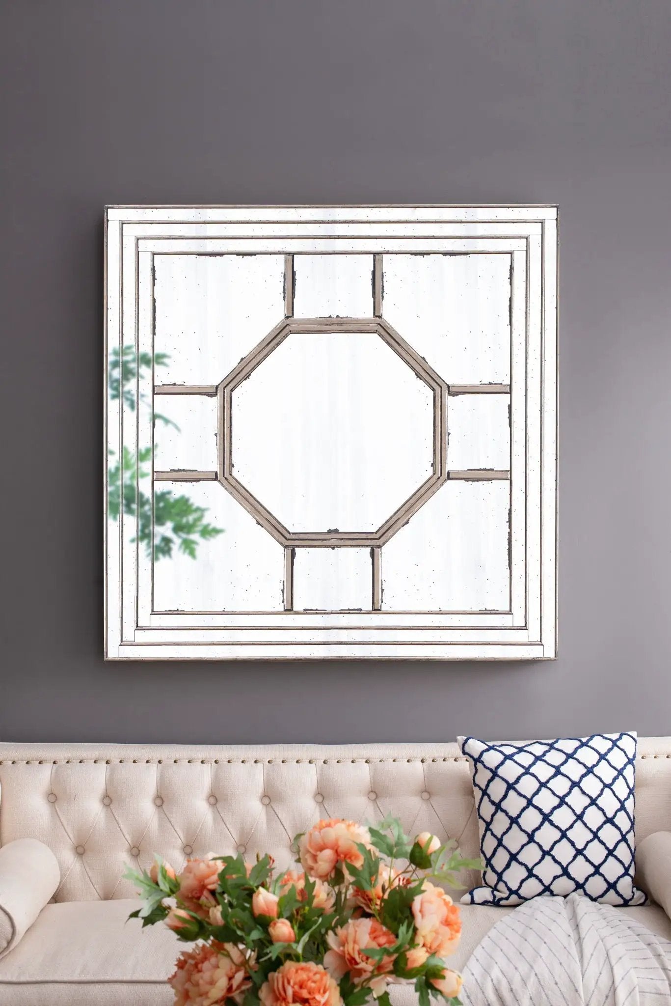Antique style square wall mirror with silver frame leaning on gray wall above beige sofa on Tampa Home & Garden Store