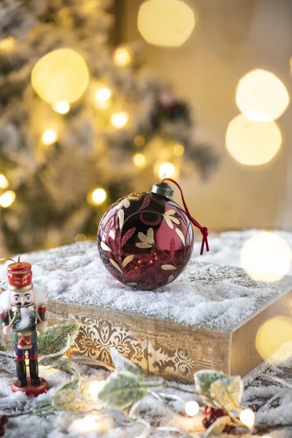 Christmas glass ball ornament burgundy with gold leaf pattern, red string, on snowy box on Tampa Home & Garden Store