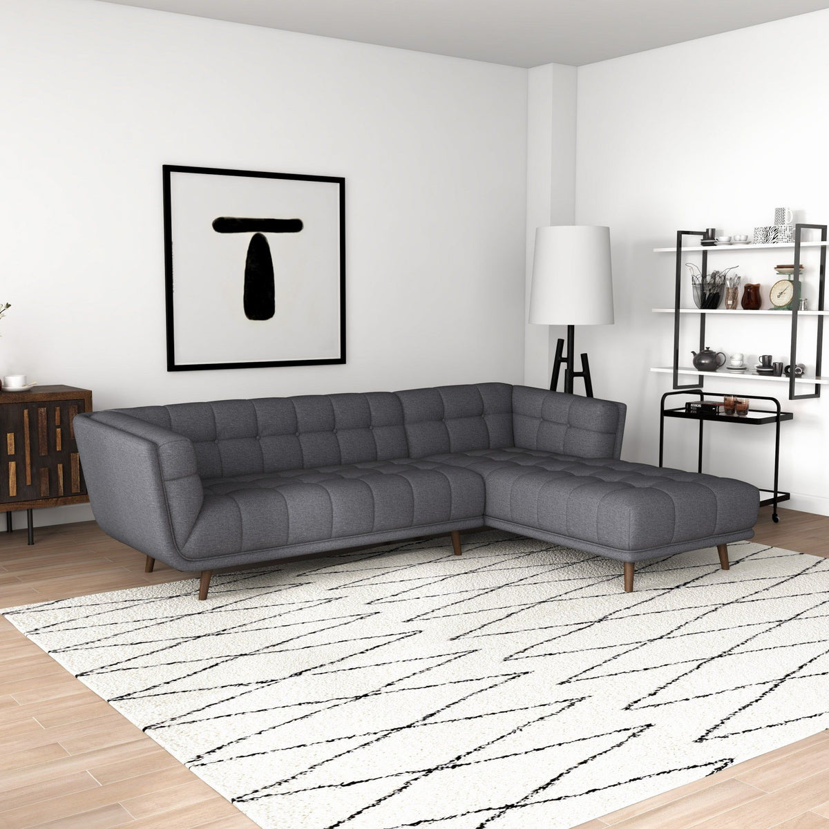 L-shaped tufted sectional sofa in dark gray with mid-century modern legs in a living room on Tampa Home & Garden Store