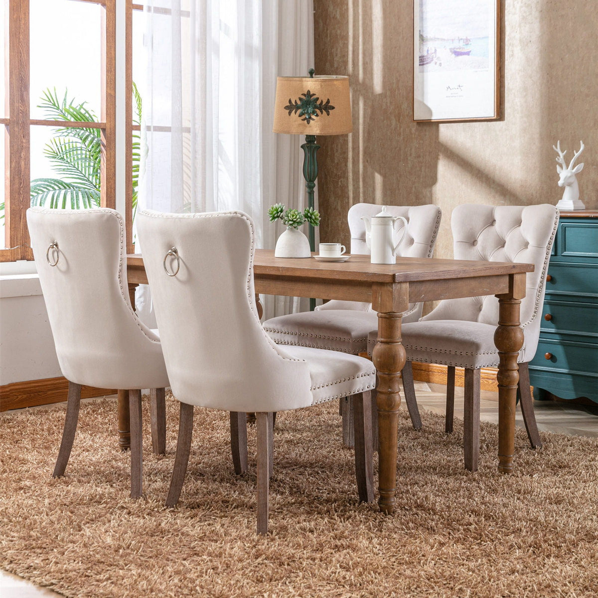 Tufted velvet dining chairs in cream with nailhead trim and ring pulls, four around a table on Tampa Home & Garden Store