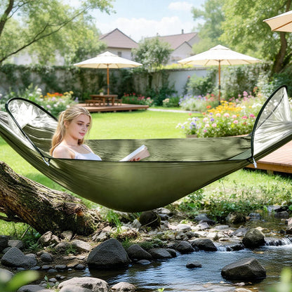 Camping hammock in olive green fabric, person reading in a garden beside a stream on Tampa Home & Garden Store