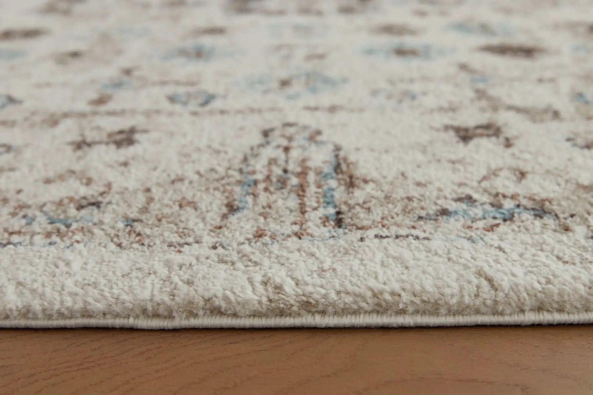 Jossler rug by Unique Piece Furniture, beige plush area rug with blue/brown accents edge binding on Tampa Home & Garden Store