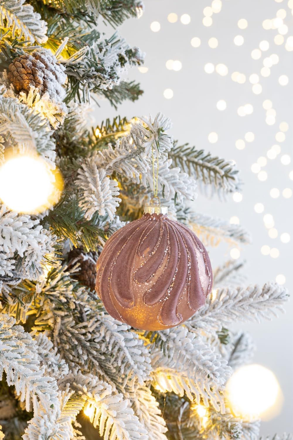 Decorative hanging glass Christmas ball ornament in mauve with gold glitter on frosted tree on Tampa Home & Garden Store