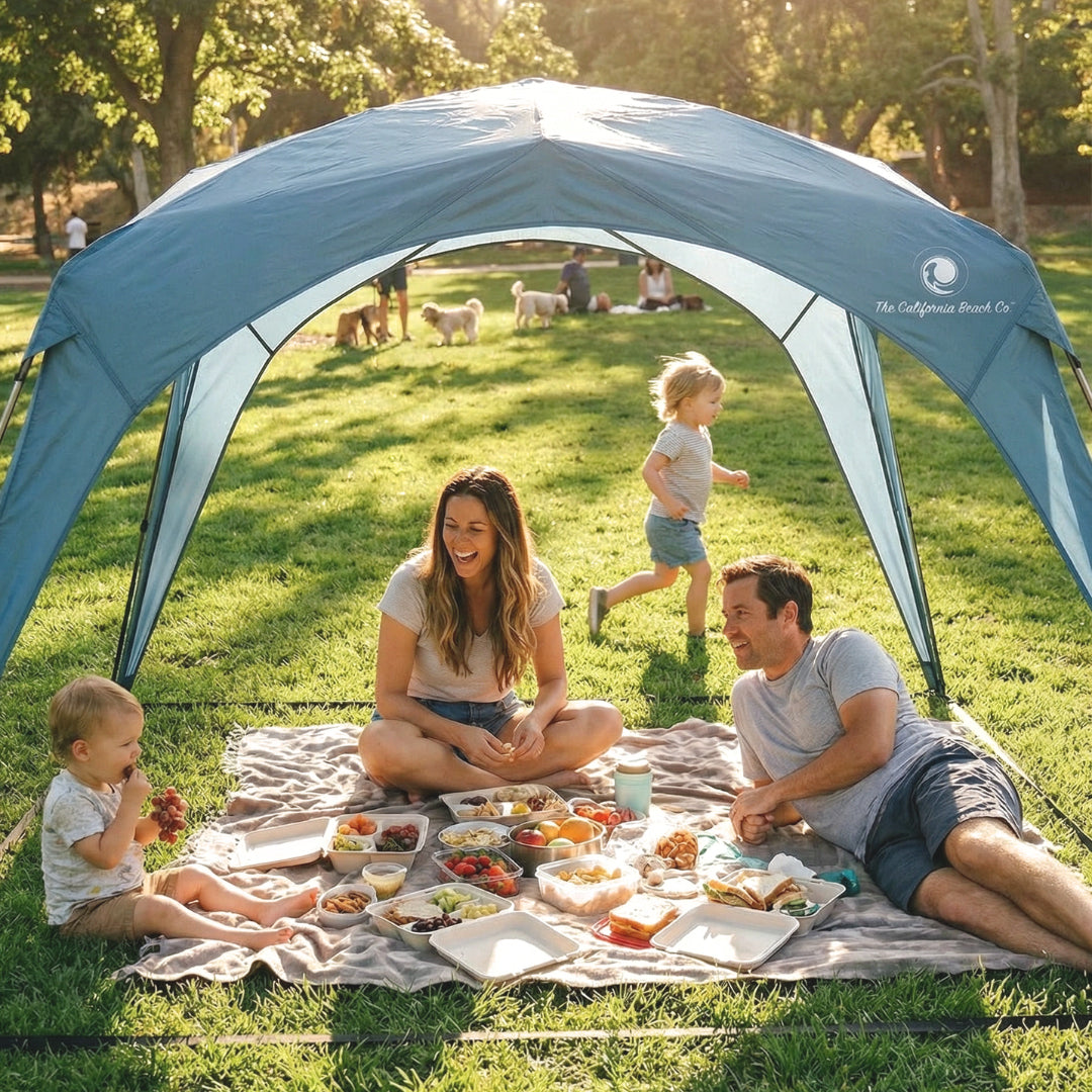 Pop 'N Go blue canopy by The California Beach Co. shelters a family picnic on a park blanket on Tampa Home & Garden Store