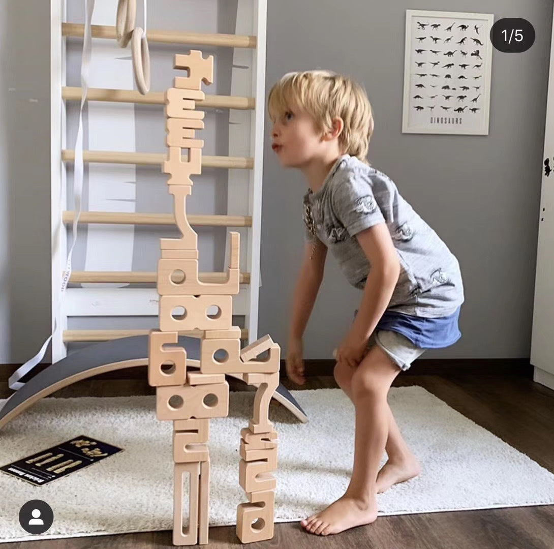 Montessori wooden blocks natural wood finish stacked into a tall tower beside a child on Tampa Home & Garden Store