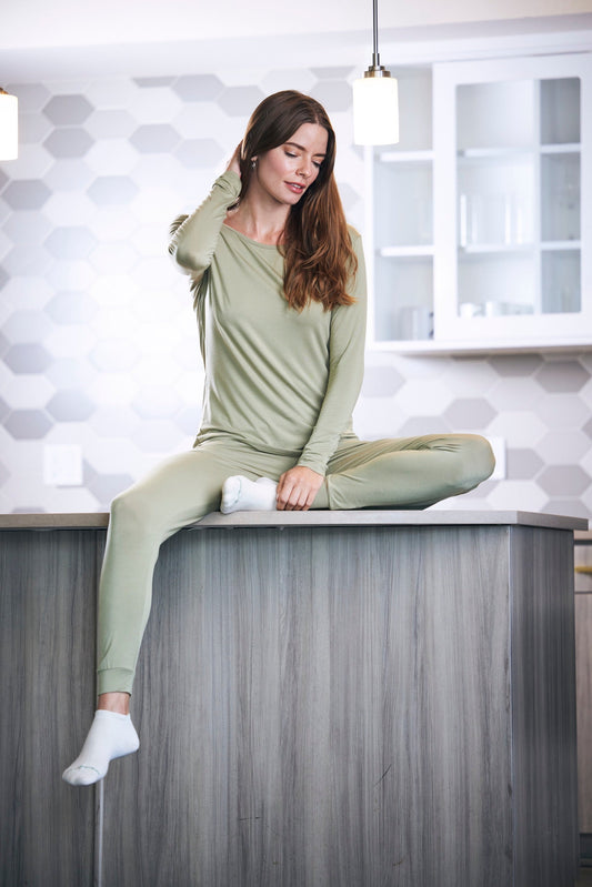 Spun Bamboo women's lounge set with long sleeve top and jogger pants in sage green worn by model in a modern kitchen on Tampa Home & Garden Store