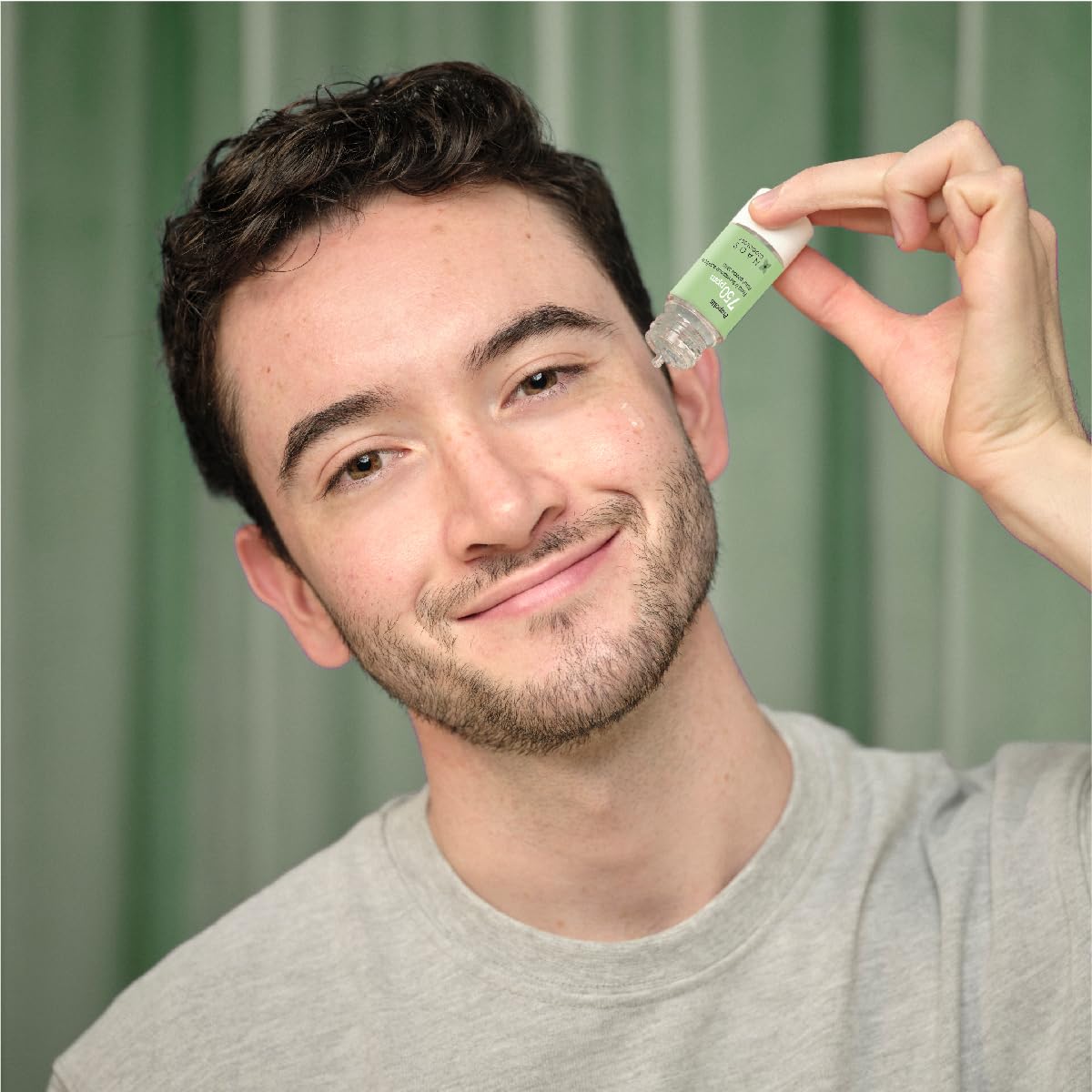 Etat Pur Zinc Gluconate Anti-Shine Serum bottle with green label for oily skin held smiling man on Tampa Home & Garden Store