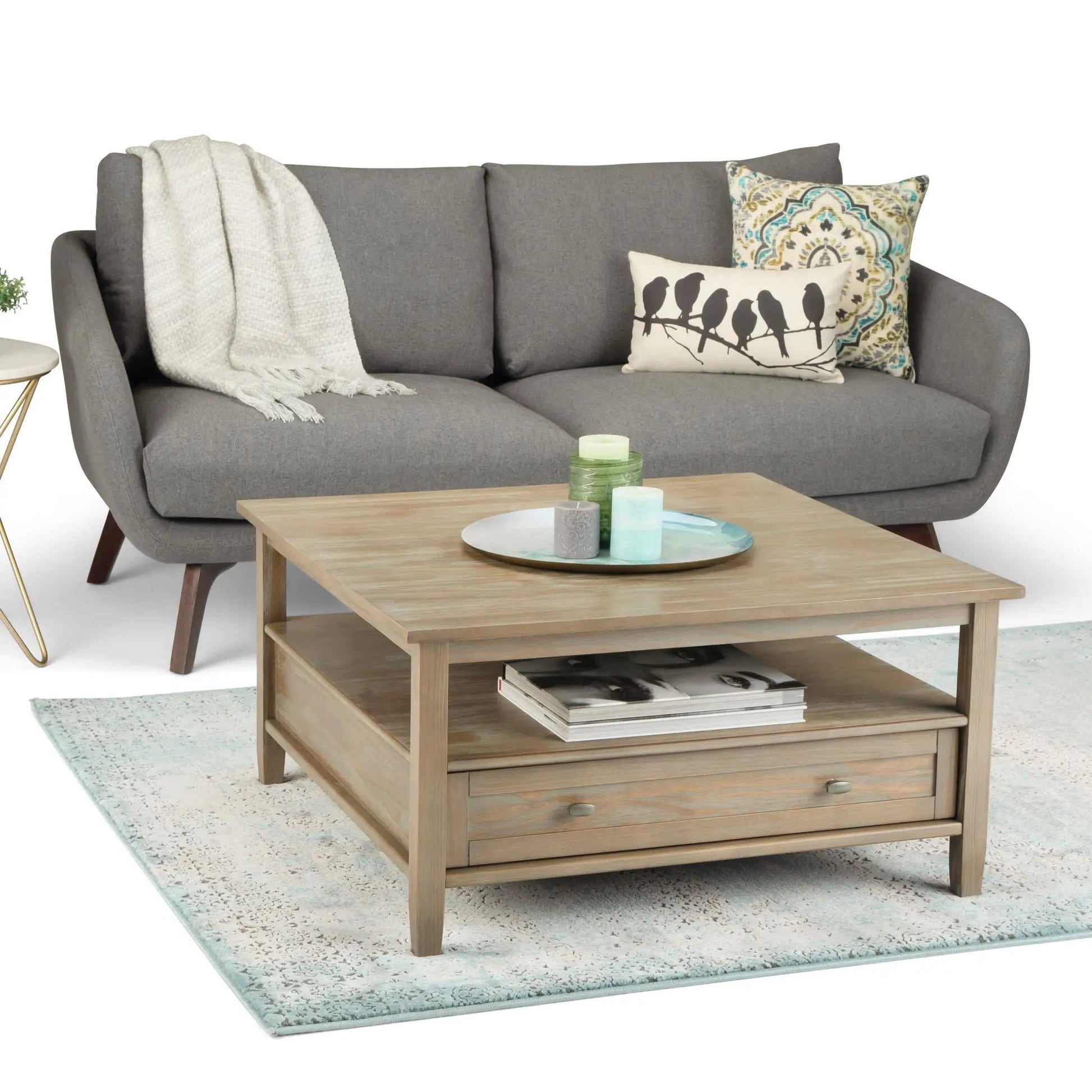 Warm Shaker coffee table with light wood finish and two lower shelves beside gray sofa on Tampa Home & Garden Store