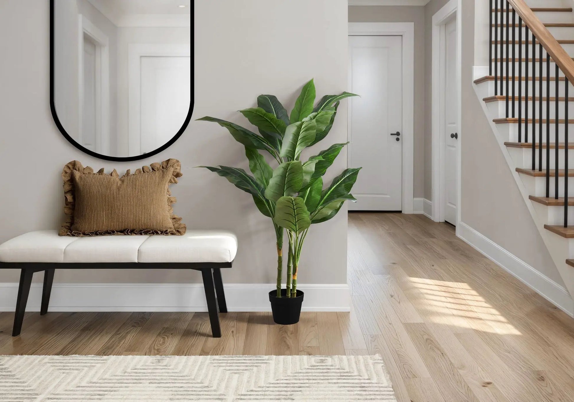 Artificial plant with large green tropical leaves in a black pot by a hallway on Tampa Home & Garden Store