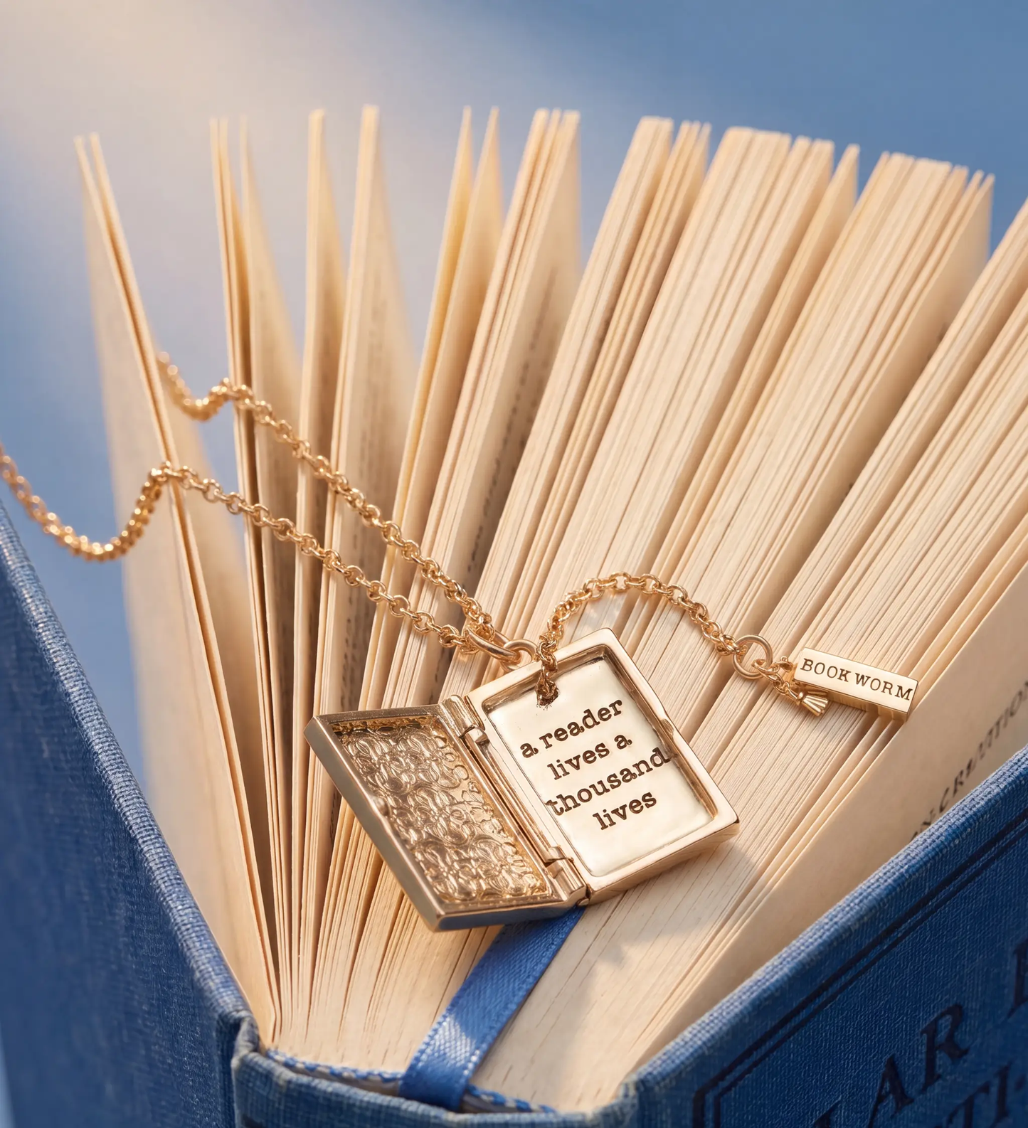 Gold-tone A Reader Lives A Thousand Lives locket necklace by ALEX AND ANI on open book pages on Tampa Home & Garden Store