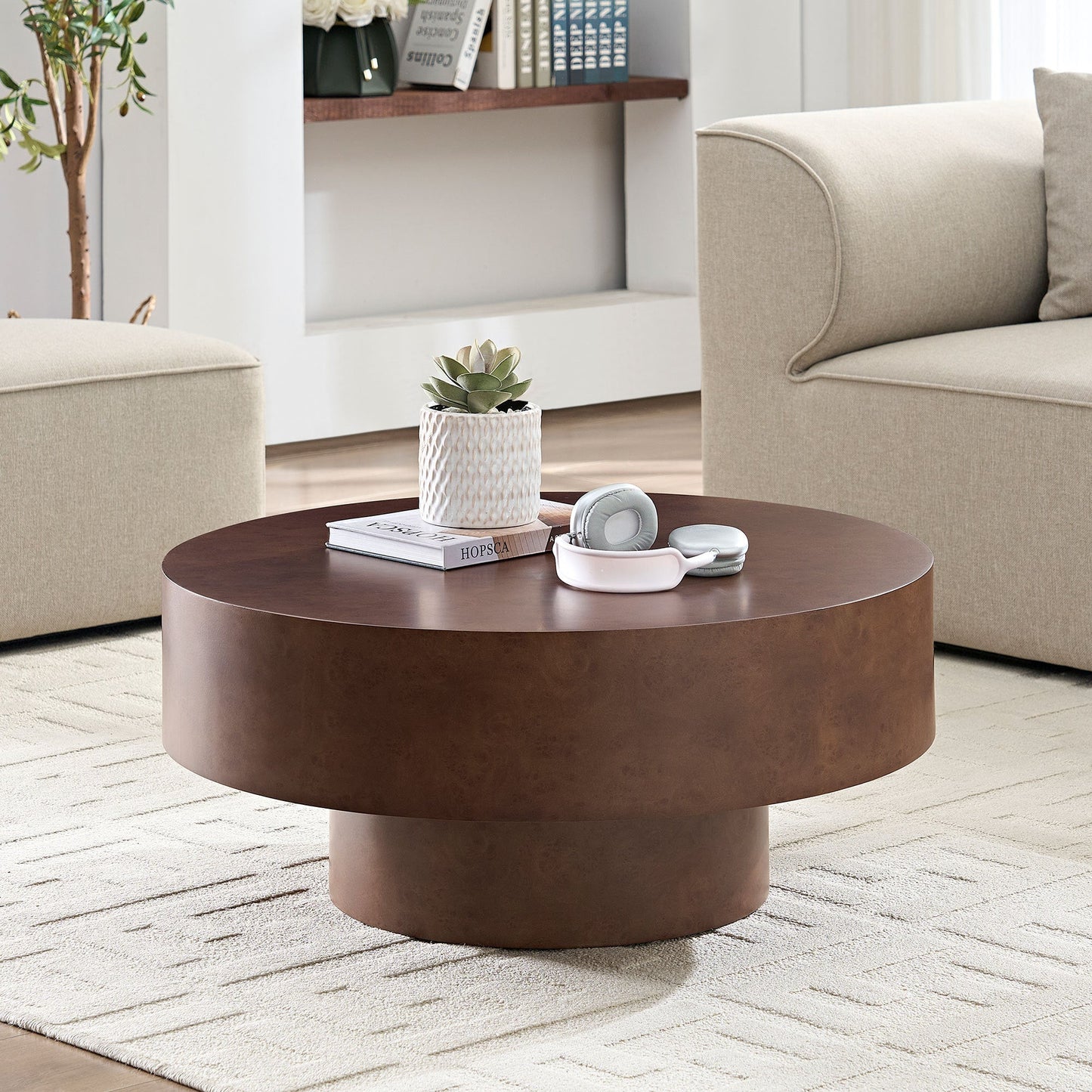 Round coffee table with faux burl wood pattern and sturdy pedestal in a beige living room on Tampa Home & Garden Store