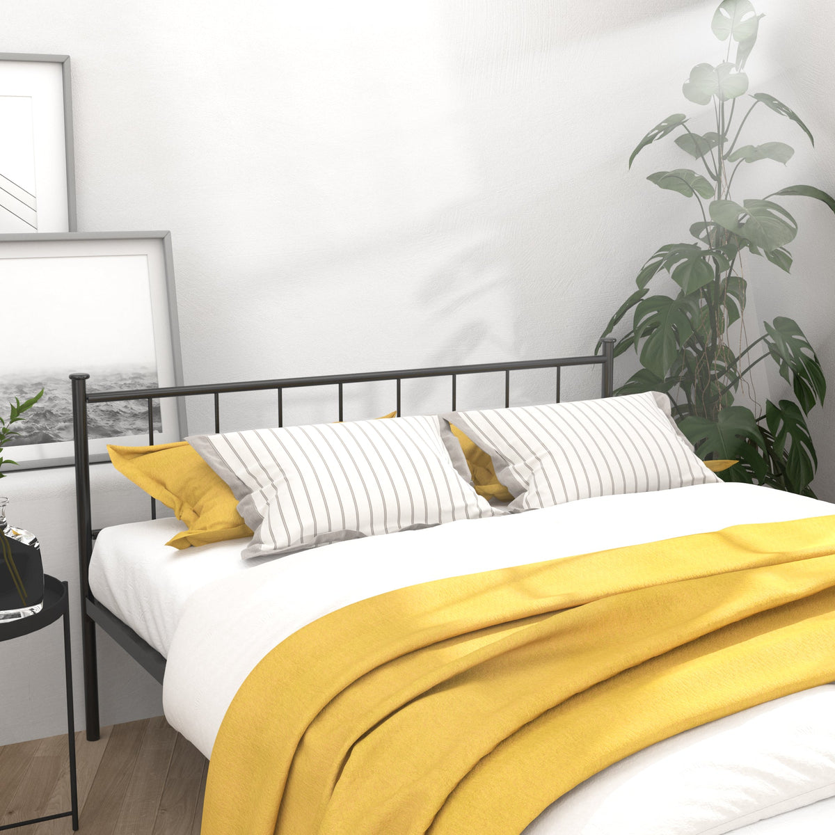 Queen size black metal bed frame; headboard and footboard, yellow bedding, framed pictures leaning on Tampa Home & Garden Store