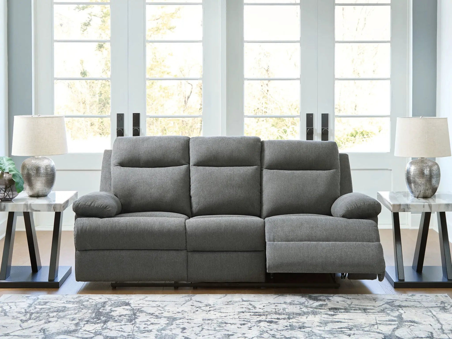 Side-Swipe gray reclining sofa with drop-down table, flanked by marble-top end tables and lamps on Tampa Home & Garden Store