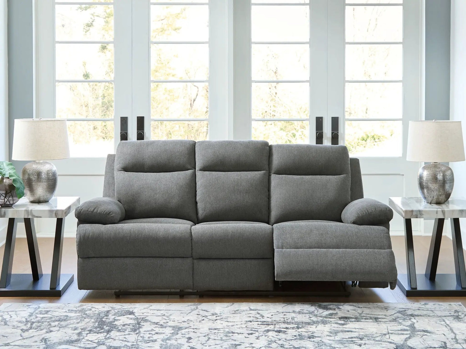 Side-Swipe gray reclining sofa with drop-down table, flanked by marble-top end tables and lamps on Tampa Home & Garden Store