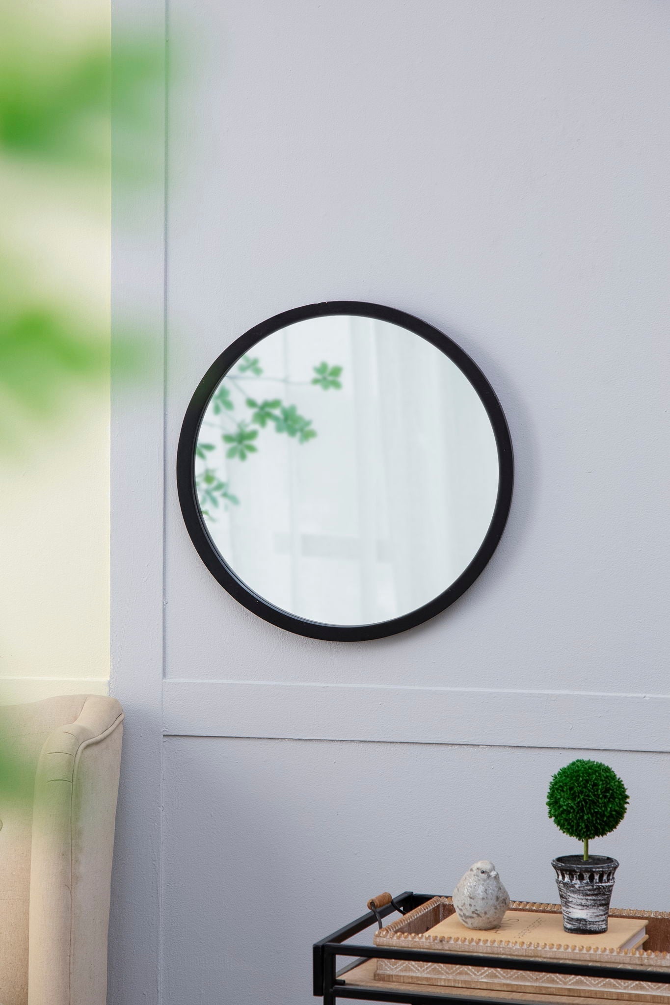 Circle wall mirror with black frame mounted on a soft gray living room wall on Tampa Home & Garden Store