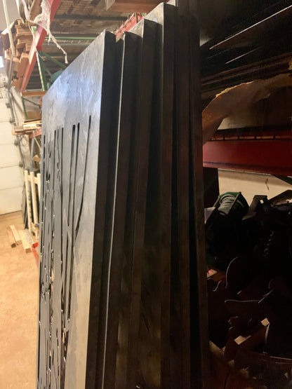 Outdoor metal privacy fence panels by Rustica Ornamentals in dark steel, stacked on a rack on Tampa Home & Garden Store