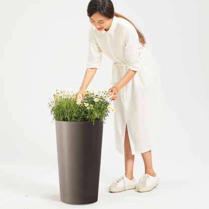 Planter For Outdoor dark gray planter with white daisies, tended by a woman in a white dress on Tampa Home & Garden Store