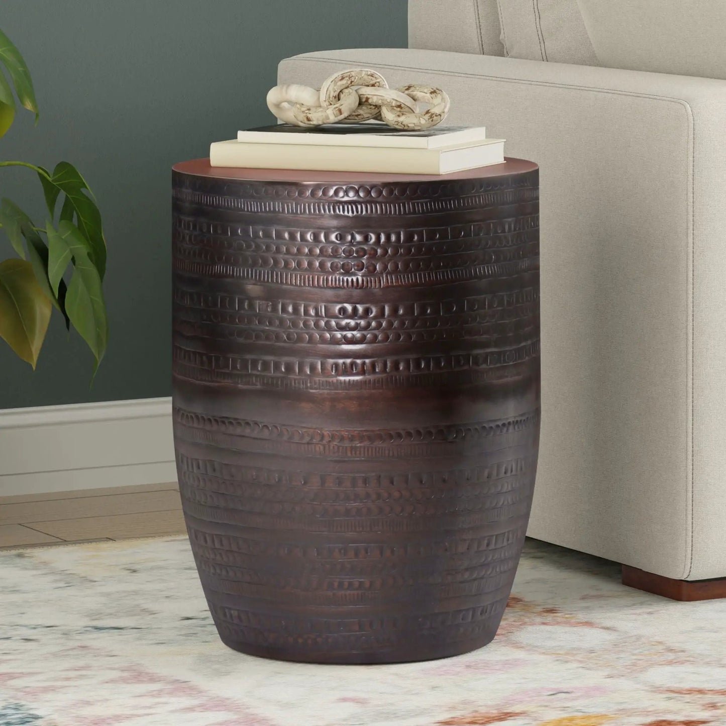 Johnsen Handcrafted Large Metal Accent Table with dark bronze drum texture and stacked books on Tampa Home & Garden Store