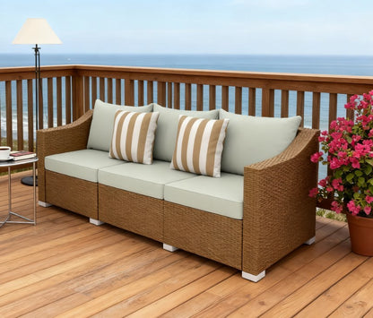 Rattan wicker outdoor sofa with cream cushions and striped pillows on a wooden deck on Tampa Home & Garden Store