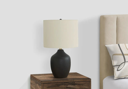 Table lamp with black ceramic base and cream fabric shade on a wood nightstand on Tampa Home & Garden Store