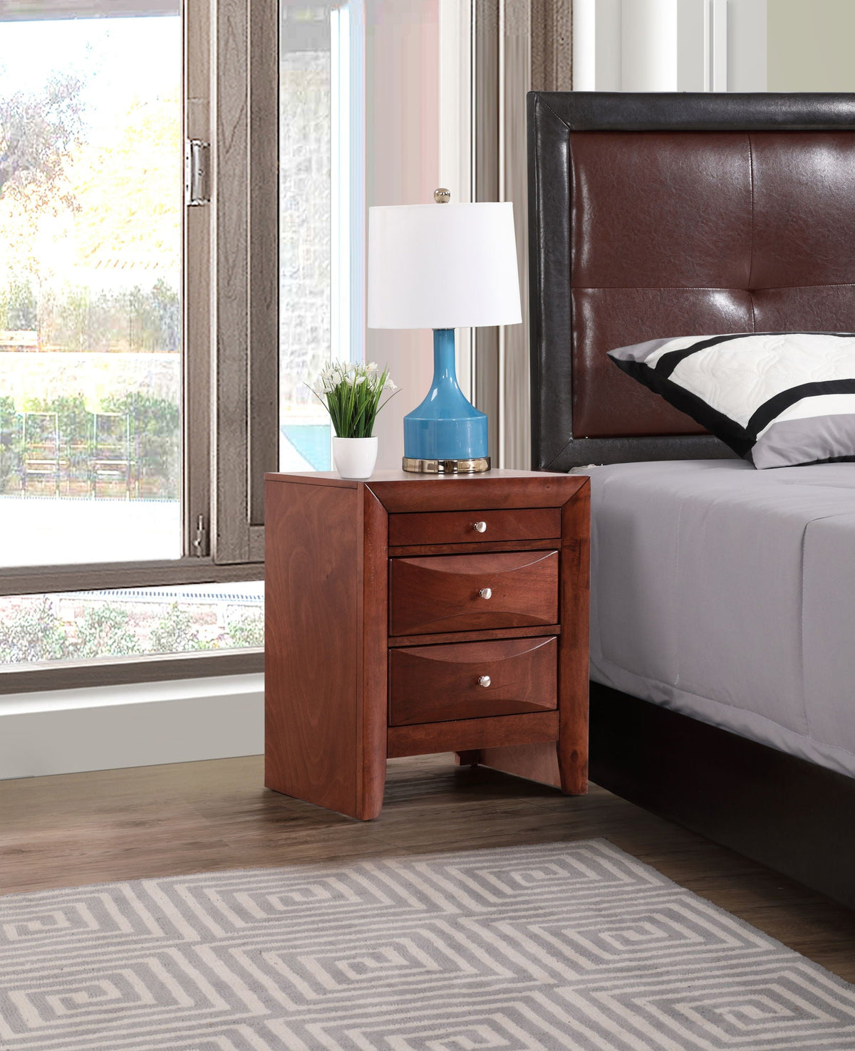 Accent nightstand with three drawers in warm cherry wood veneer beside bed on Tampa Home & Garden Store