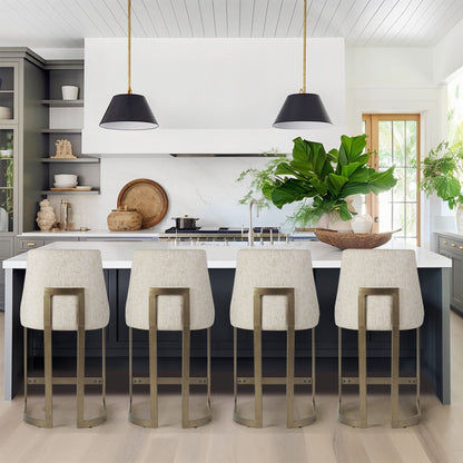Upholstered counter stools with gold metal bases in cream fabric along a white kitchen island on Tampa Home & Garden Store