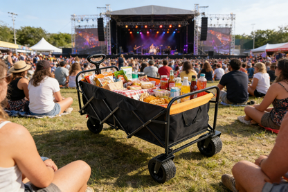 Folding wagon cart with extender, black and orange, loaded with snacks at an outdoor concert on Tampa Home & Garden Store