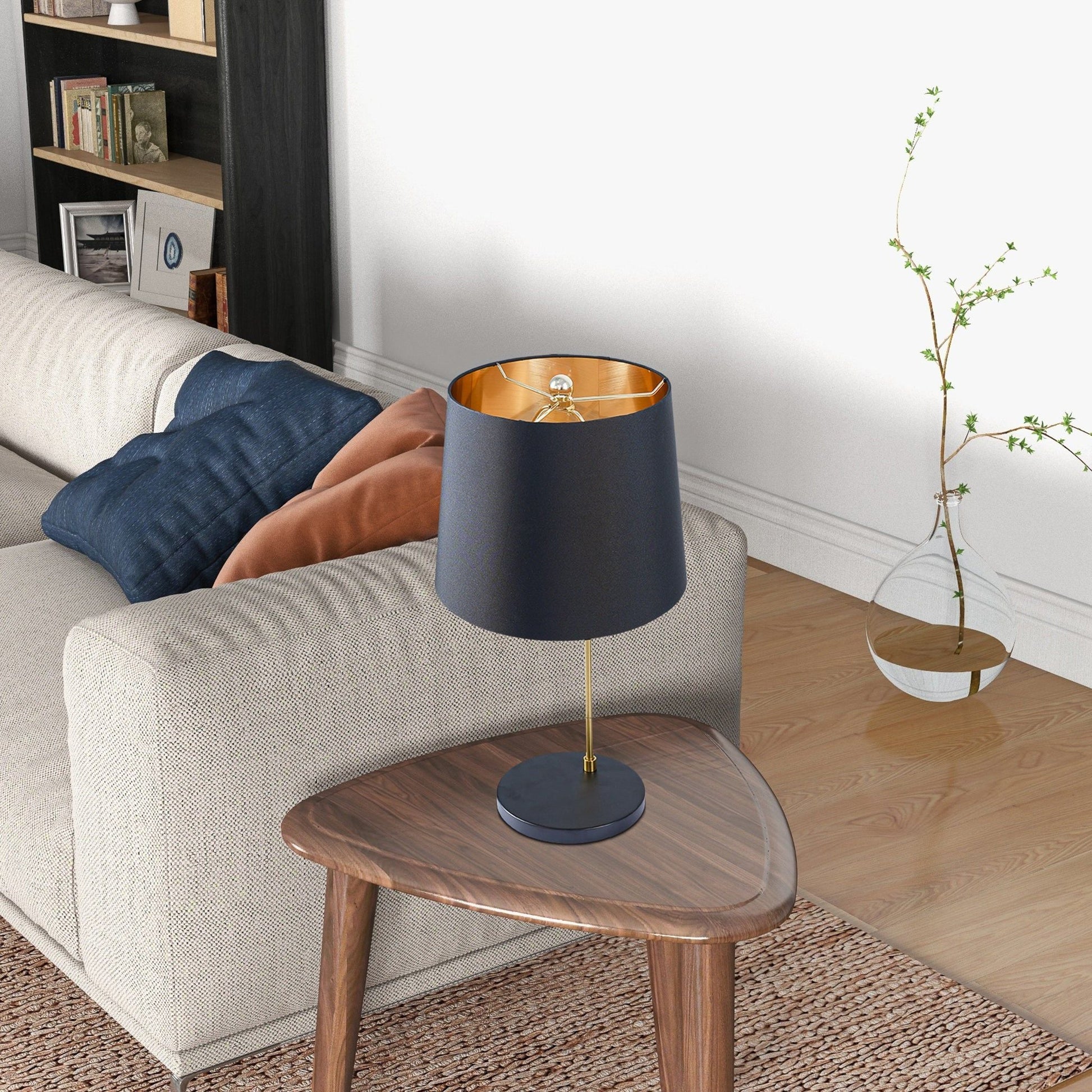 Desk lamp with black shade and brass stem featuring a gold interior on a round wood side table on Tampa Home & Garden Store