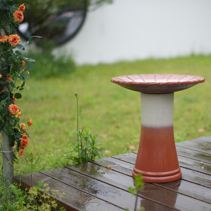 HouseOfZazla handmade glazed ceramic bird bath on a two-tone pedestal beside orange roses on Tampa Home & Garden Store