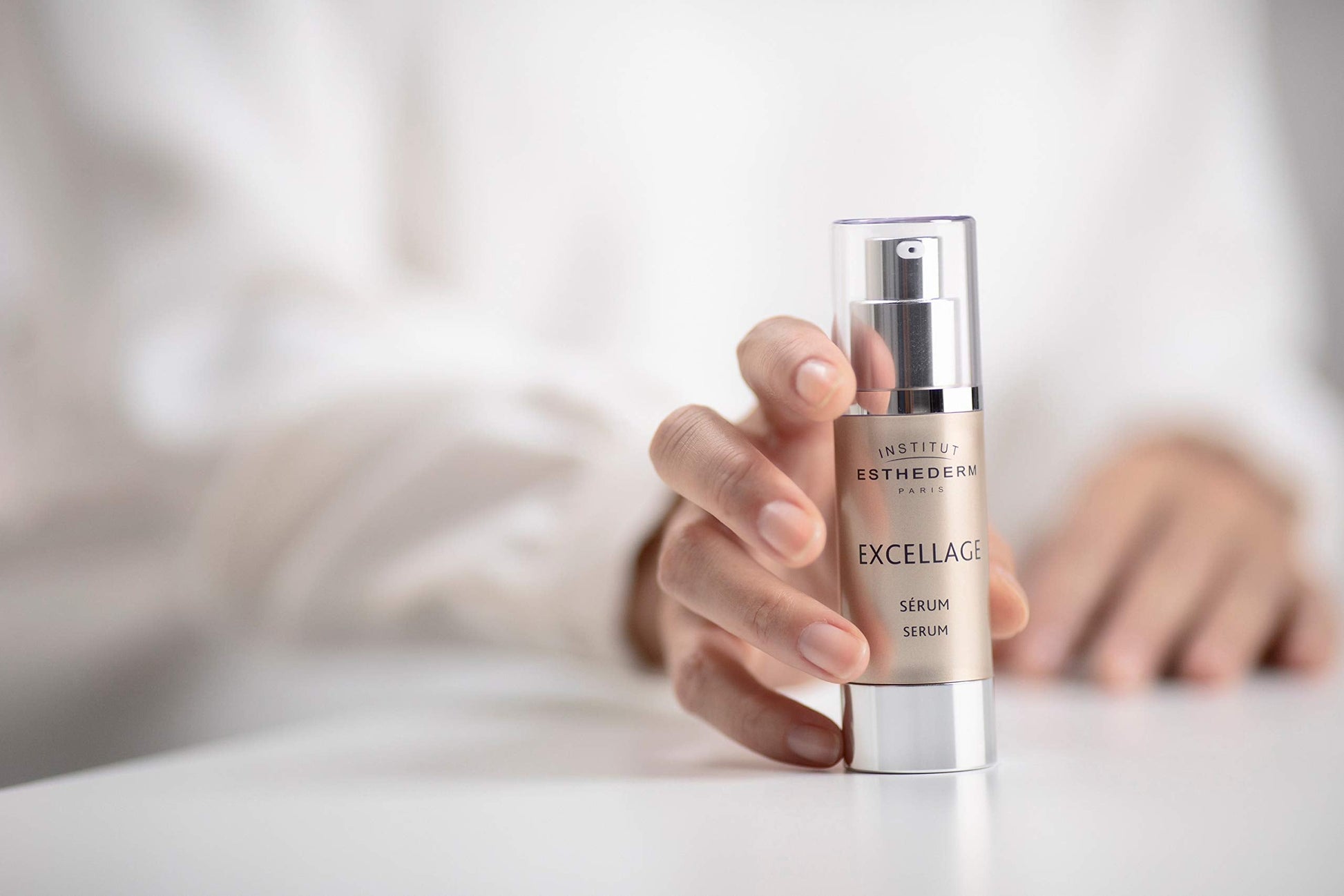 Institut Esthederm Excellage serum bottle with beige body and silver pump held in hand on Tampa Home & Garden Store