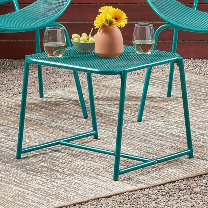 Two teal outdoor iron chairs with mesh seats around a teal mesh table with a yellow flower vase on Tampa Home & Garden Store